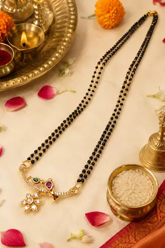 Traditional double strand black bead mangalsutra with gold-toned floral cz pendant, ruby & emerald accents