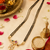 Traditional double strand black bead mangalsutra with gold-toned floral cz pendant, ruby & emerald accents