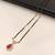 Gold-toned mangalsutra with ruby red teardrop pendant, black bead chain, cz stone accents