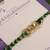 Golden chain green thread rakhi with roli chawal capsules
