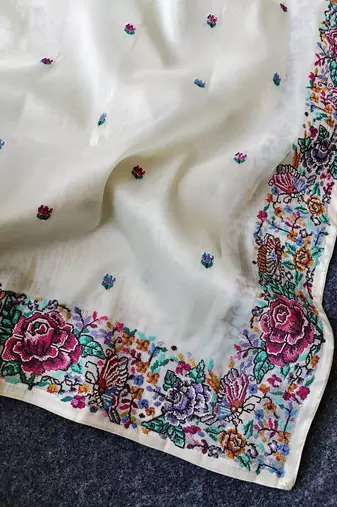 White tissue viscose saree features a heavy floral embroidered border and all-over buttis