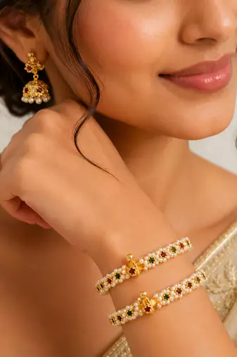 Pearl bangle with red and green stone accents, gold-toned, openable, 