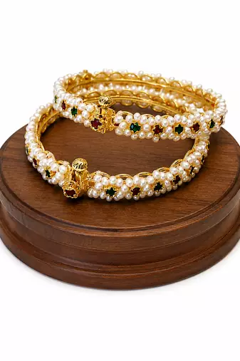 Pearl bangle with red and green stone accents, gold-toned, openable, 