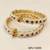 Pearl bangle with red and green stone accents, gold-toned, openable, 