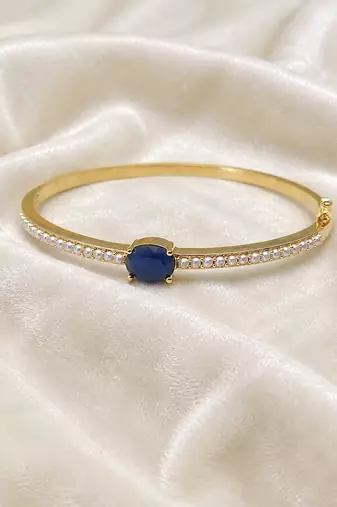 Gold-toned kada bangle with blue oval stone and pearl accents openable free size 