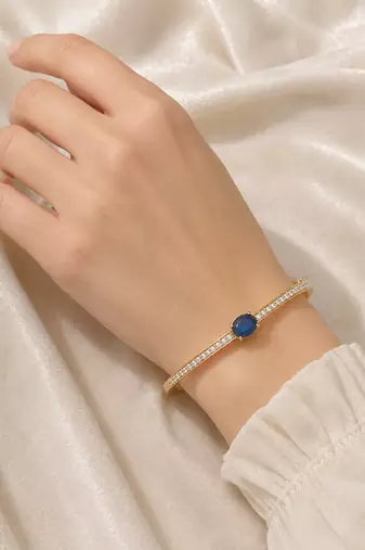 Gold-toned kada bangle with blue oval stone and pearl accents openable free size 
