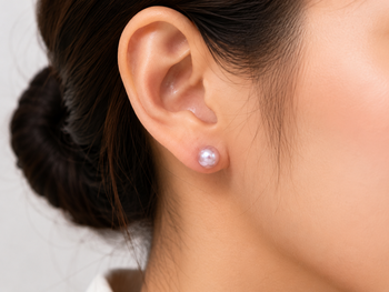 Pink freshwater pearl stud earrings with gold-tone backs pushing 2