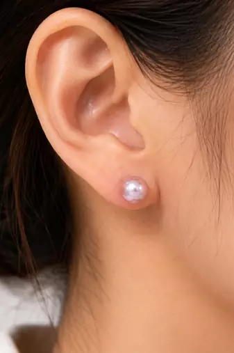Pink freshwater pearl stud earrings with gold-tone backs pushing