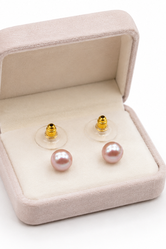 Pink freshwater pearl stud earrings with gold-tone backs pushing