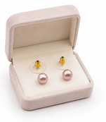 Pink freshwater pearl stud earrings with gold-tone backs pushing