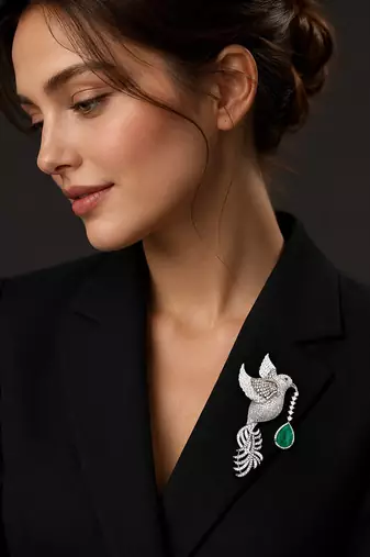 Silver-toned flying bird brooch with green teardrop crystal 