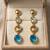 Gold tone drop earrings with multi-color crystal stones, dangle style, blue peach clear gems