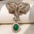 Gold plated green stone twin elephant brooch