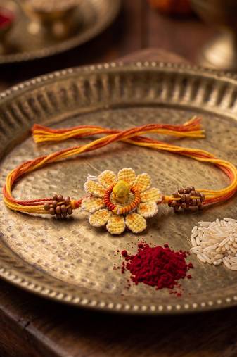 yellow floral seed thread rakhi with roli chawal chandan mishri