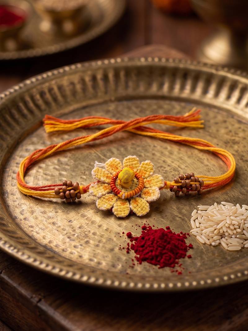 yellow floral seed thread rakhi with roli chawal chandan mishri