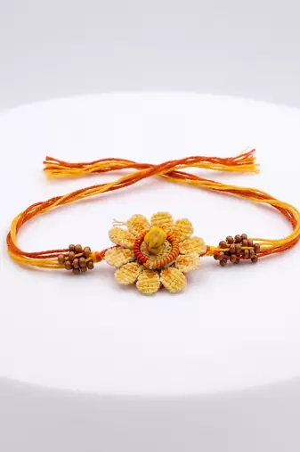 yellow floral seed thread rakhi with roli chawal chandan mishri