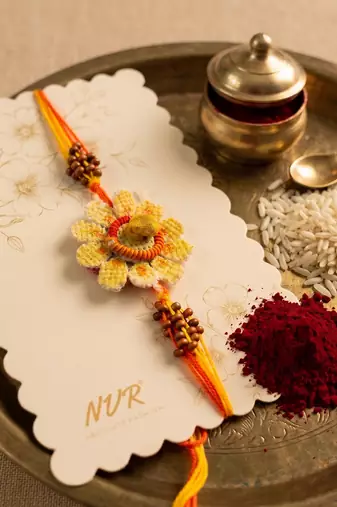 yellow floral seed thread rakhi with roli chawal chandan mishri