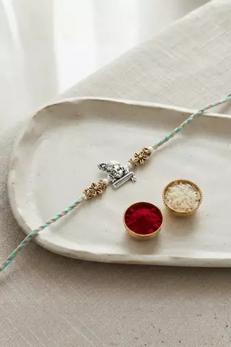 ganesha design rakhi with roli chawal and raksha bandhan card