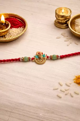 ganesha designer red rakhi with roli chawal and raksha bandhan card