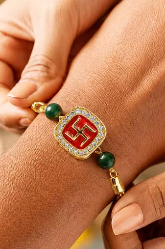 Gold-tone swastik designer rakhi with green beads