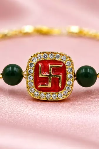 Gold-tone swastik designer rakhi with green beads