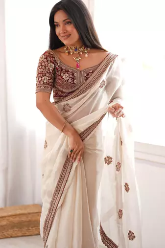 Cream tissue satin embroidered saree with unstitched blouse piece.