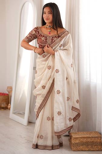 Cream tissue satin embroidered saree with unstitched blouse piece.
