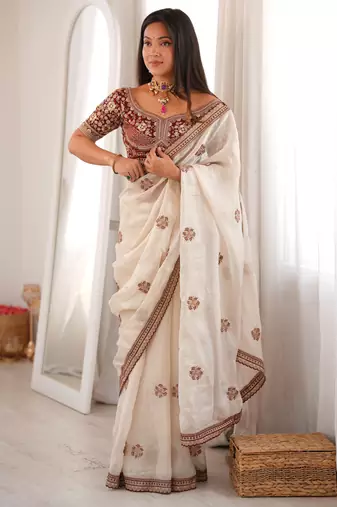 Cream tissue satin embroidered saree with unstitched blouse piece.