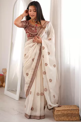 Cream tissue satin embroidered saree with unstitched blouse piece.