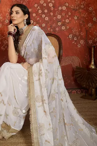 Cream tissue satin embroidered sequin saree with unstitched blouse piece.