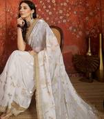 Cream tissue satin embroidered sequin saree with unstitched blouse piece.