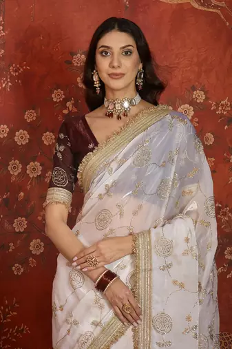Cream tissue satin embroidered sequin saree with unstitched blouse piece.