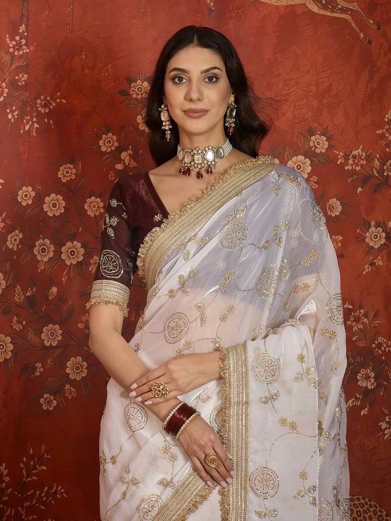 Cream tissue satin embroidered sequin saree with unstitched blouse piece.