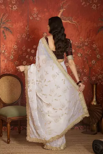 Cream tissue satin embroidered sequin saree with unstitched blouse piece.