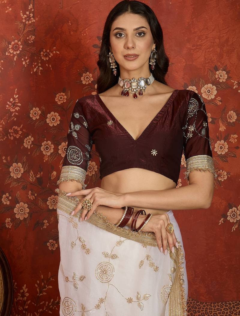 Cream tissue satin embroidered sequin saree with unstitched blouse piece.