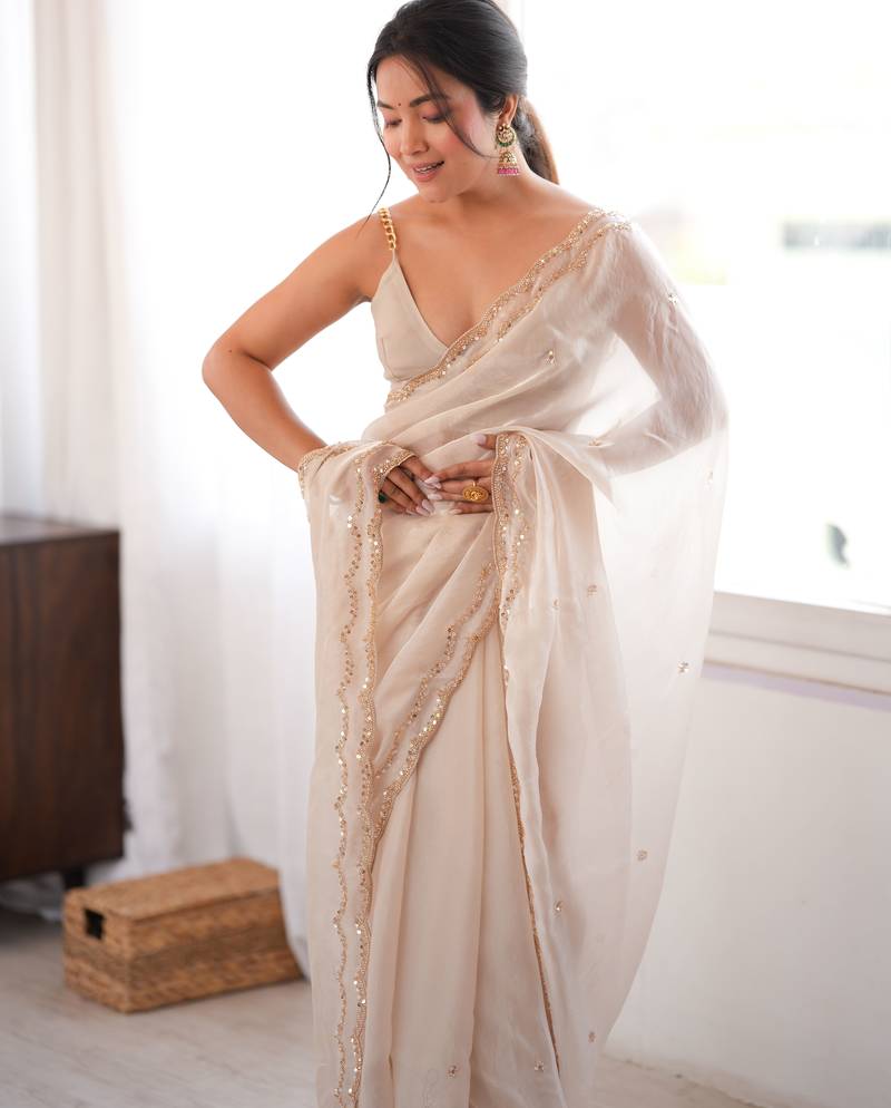 Cream tissue satin sequins saree with unstitched blouse piece.