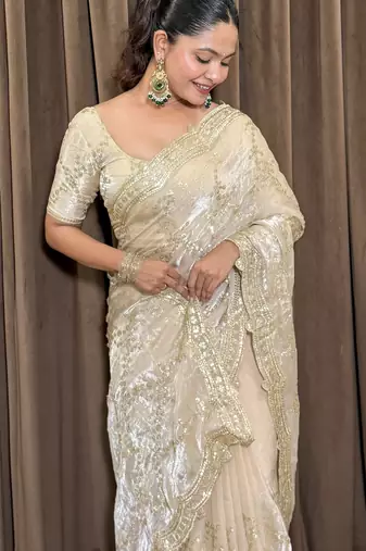 Cream tissue satin embroidered saree with unstitched blouse piece.