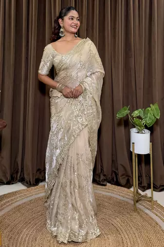 Cream tissue satin embroidered saree with unstitched blouse piece.
