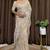 Cream tissue satin embroidered saree with unstitched blouse piece.