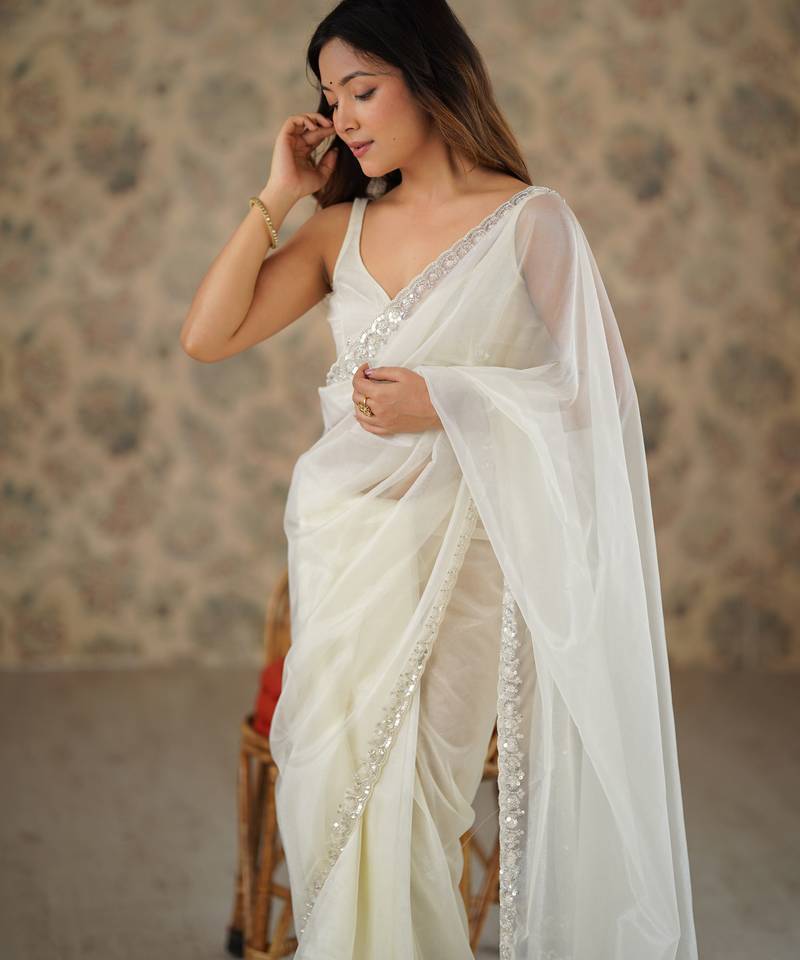 Cream net embellished saree with unstitched blouse piece.