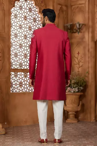 Red indo-western sherwani set with full computer embroidery, coloured buttons, and thread, lace, and stone work.