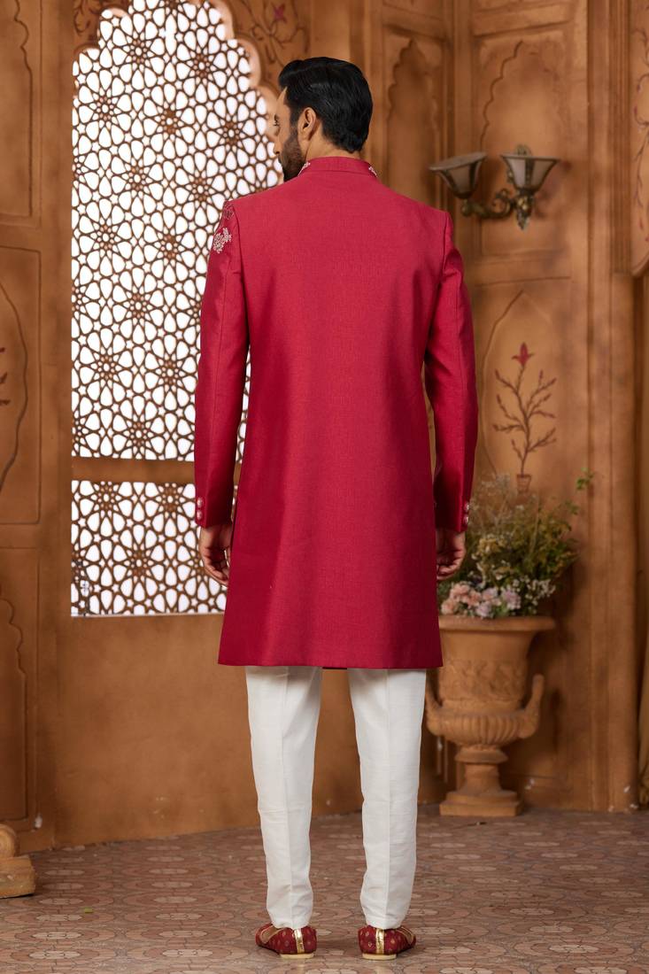 Red indo-western sherwani set with full computer embroidery, coloured buttons, and thread, lace, and stone work.
