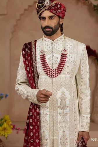 Cream heavy sherwani set with full hand embroidery, stone work, and resham thread detailing.