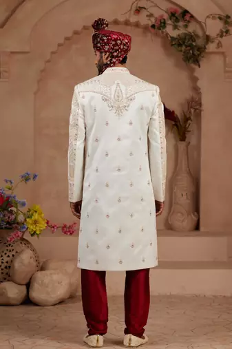 Cream heavy sherwani set with full hand embroidery, stone work, and resham thread detailing.