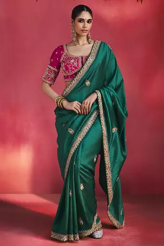 bottle green silk blend saree with rani pink embroidered blouse & zari border