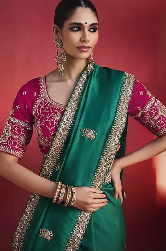 bottle green silk blend saree with rani pink embroidered blouse & zari border