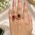 Elegant gold tone red gemstone floral statement ring with clear stone halo