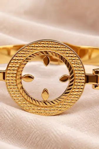 Gold-toned bangle bracelet with circular medallion & floral cutout