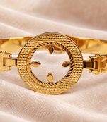 Gold-toned bangle bracelet with circular medallion & floral cutout