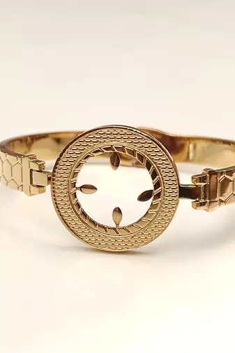 Gold-toned bangle bracelet with circular medallion & floral cutout